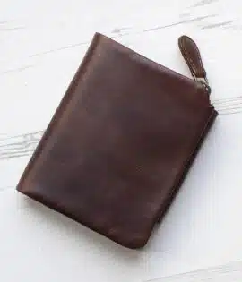 brown leather wallet with coin zipped pocket on wood background