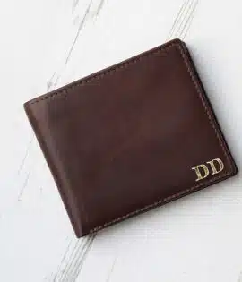 brown leather wallet with coin zipped pocket on wood background showing gold embossed initials