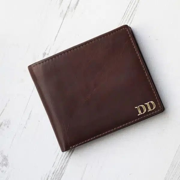 brown leather wallet with coin zipped pocket on wood background showing gold embossed initials