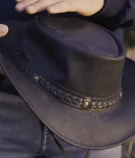 man holding a black leather hat by wombat