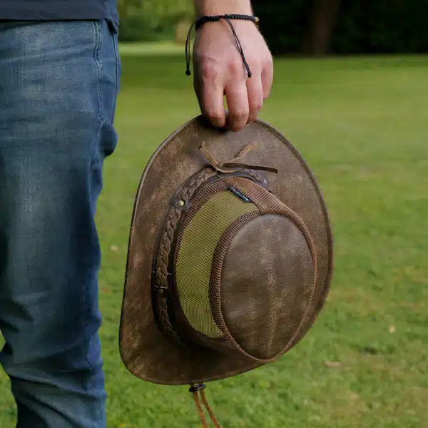 man holding a wombat the wilds air brown leather hat with mesh sides