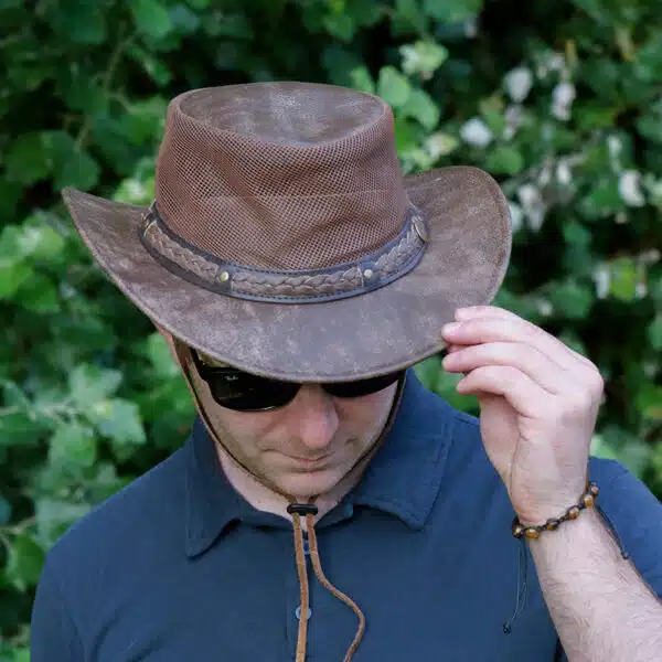 man wearing a wombat the wilds air brown leather hat with mesh sides