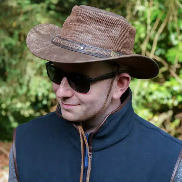 man wearing a wombat the wilds air brown leather hat with mesh sides