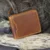 mens tan zip around leather wallet on a wood background