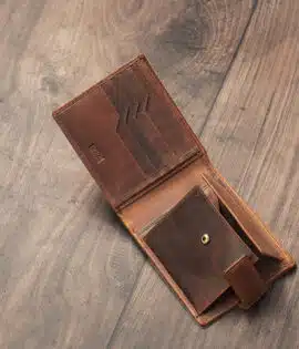 mens tan bifold wallet on a wood background open showing popper change pocket