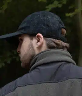 man wearing a black leather cap by wombat side veiw