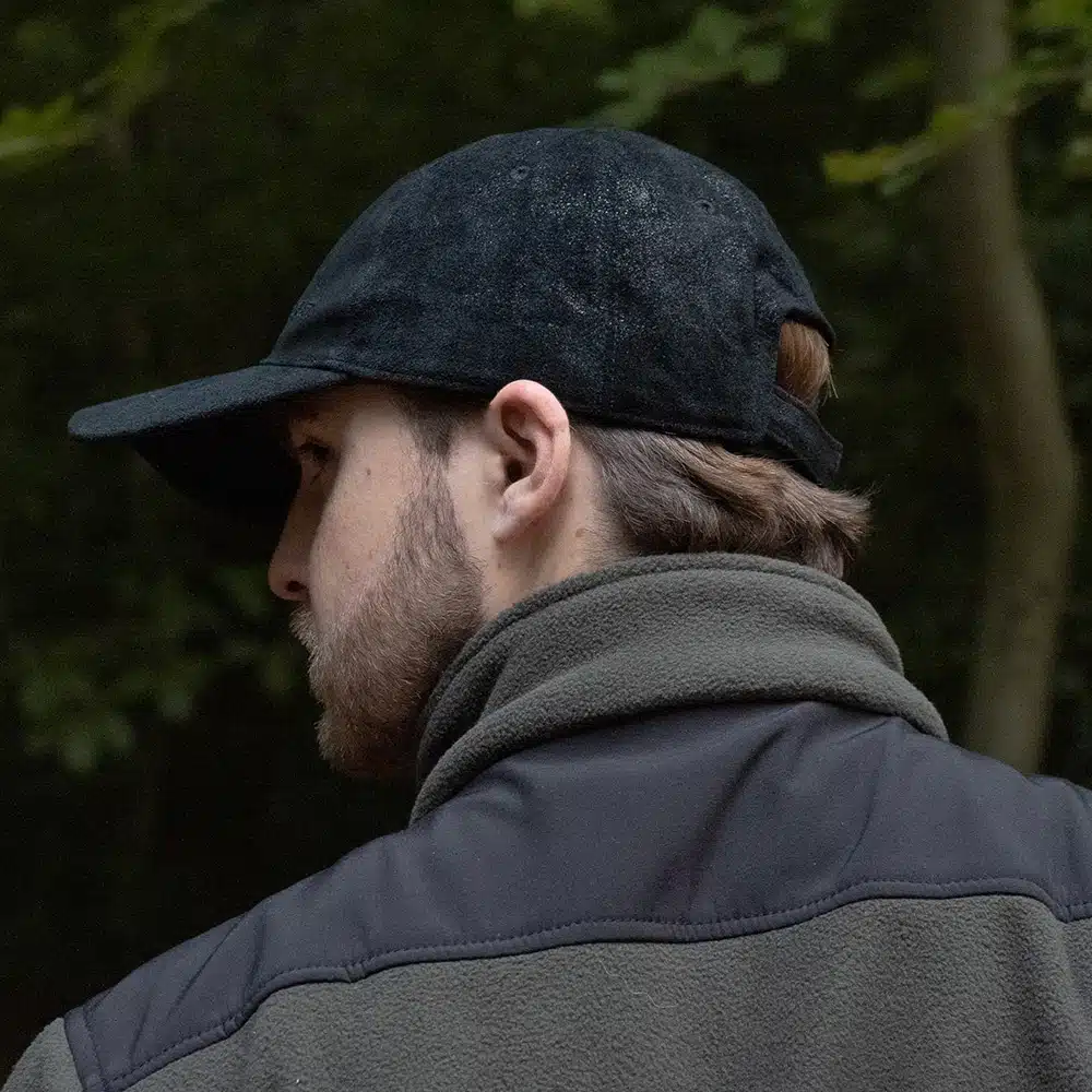 man wearing a black leather cap by wombat side veiw