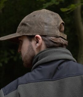 man wearing a brown leather cap by wombat side view