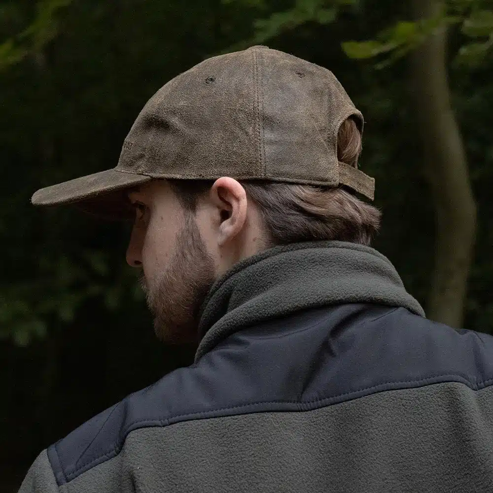man wearing a brown leather cap by wombat side view