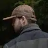 man wearing a brown leather cap by wombat side view