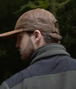 man wearing a brown leather cap by wombat side view