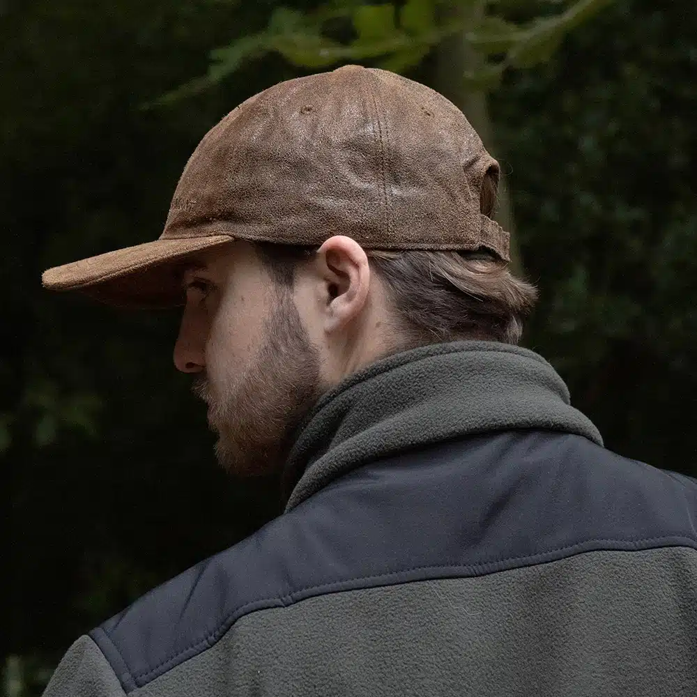 man wearing a brown leather cap by wombat side view