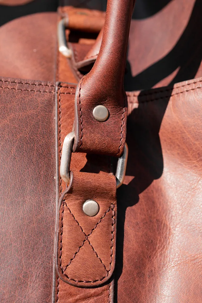 Close detail of brown leather, stitching and buckle hardware