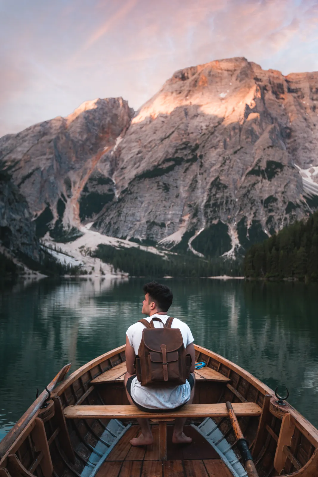 Traveller with a leather backpack in a boat on a mountain lake